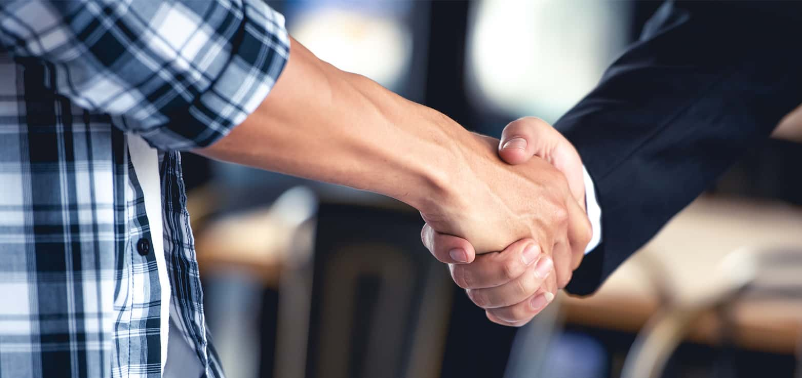 firm handshake between casually dressed person and formally dressed person