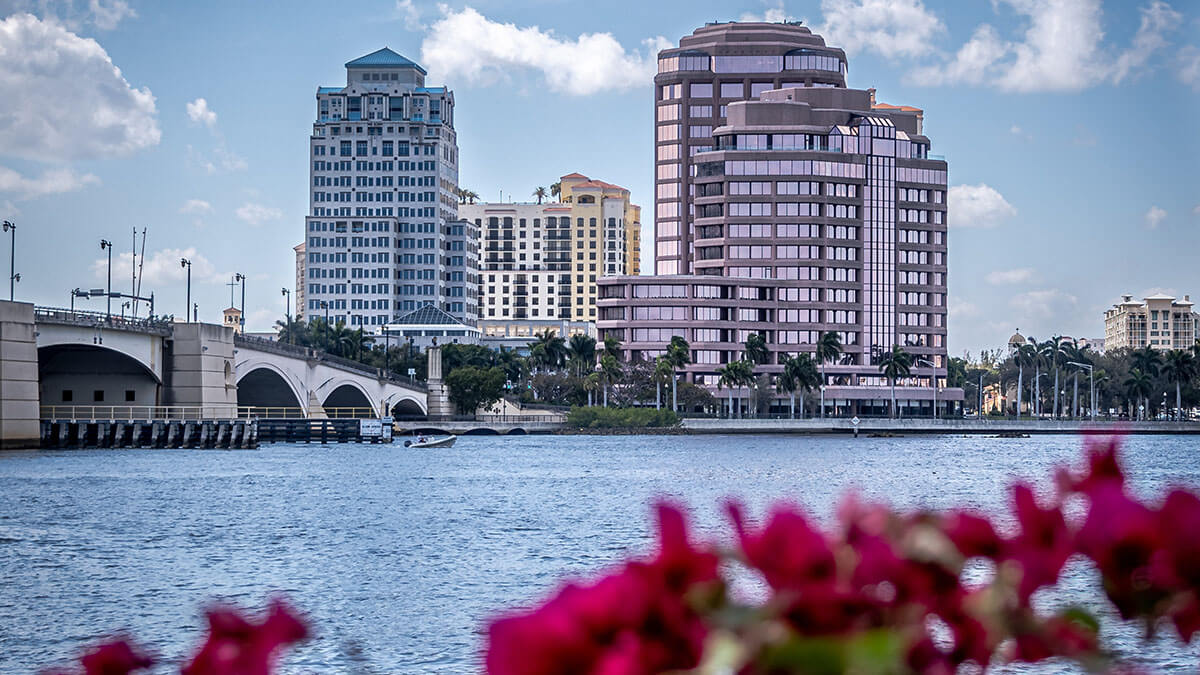 cityscape with skyscrapers and water of West Palm Beach, FL with red flowers in foreground