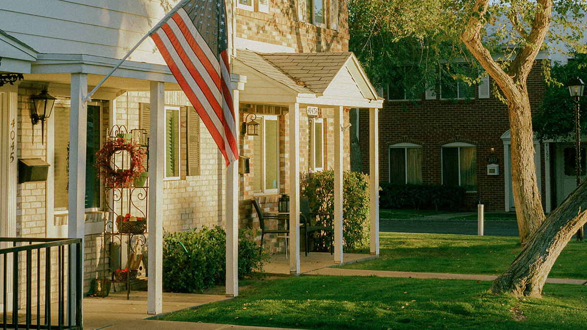 front of house with grass, trees and american flag waving at sunset