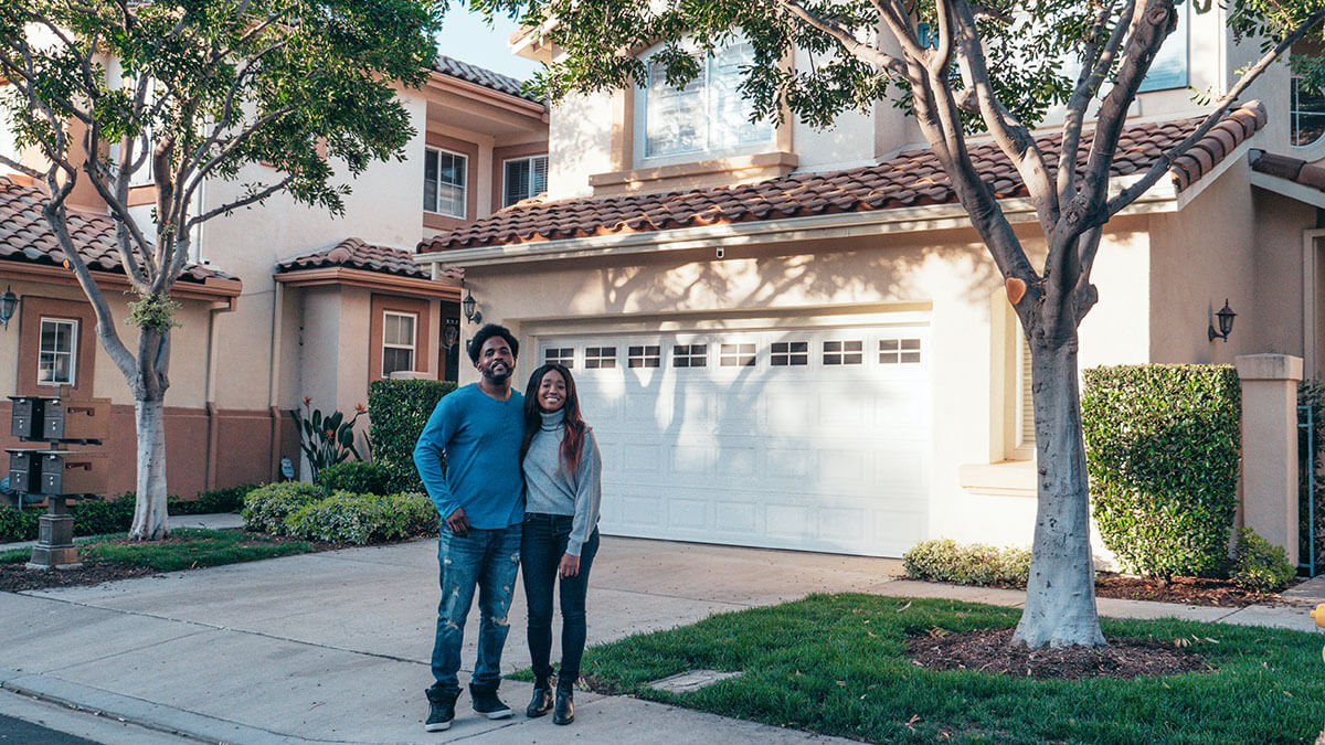 couple standing in front of a house they're trying to sell