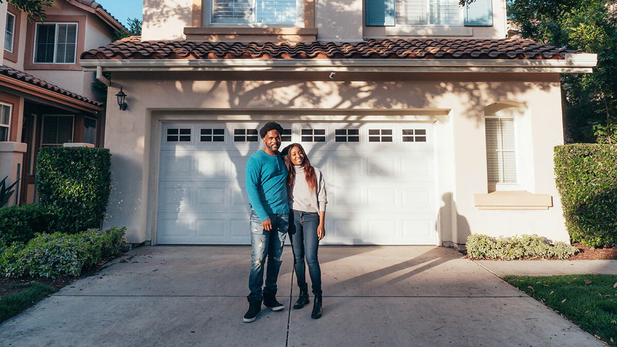 couple standing in front of house they want to sell