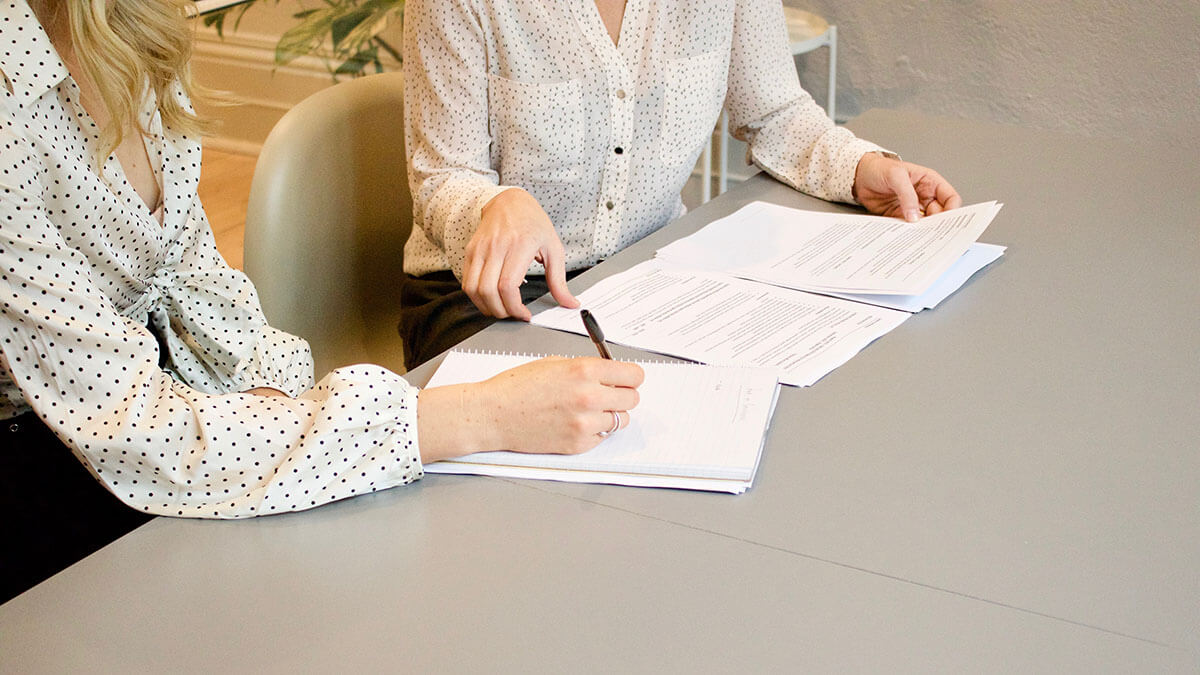 person signing document on gray table