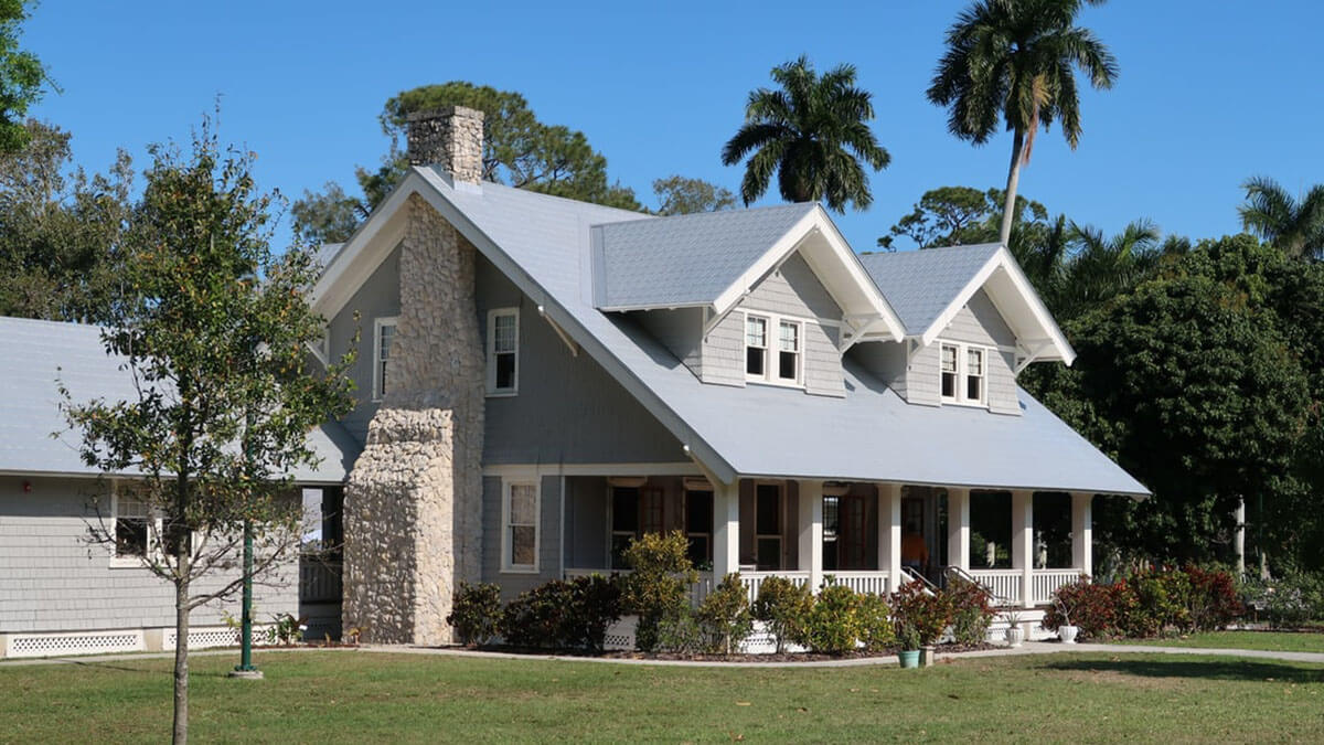 white single family house with porch with palms in background