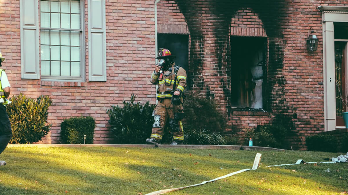 firefighter coming out of fire damaged house